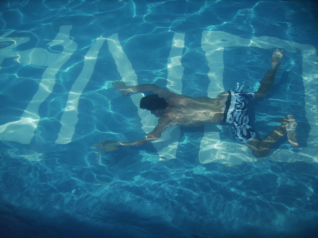 Muž plavající pod hladinou v bazénu
